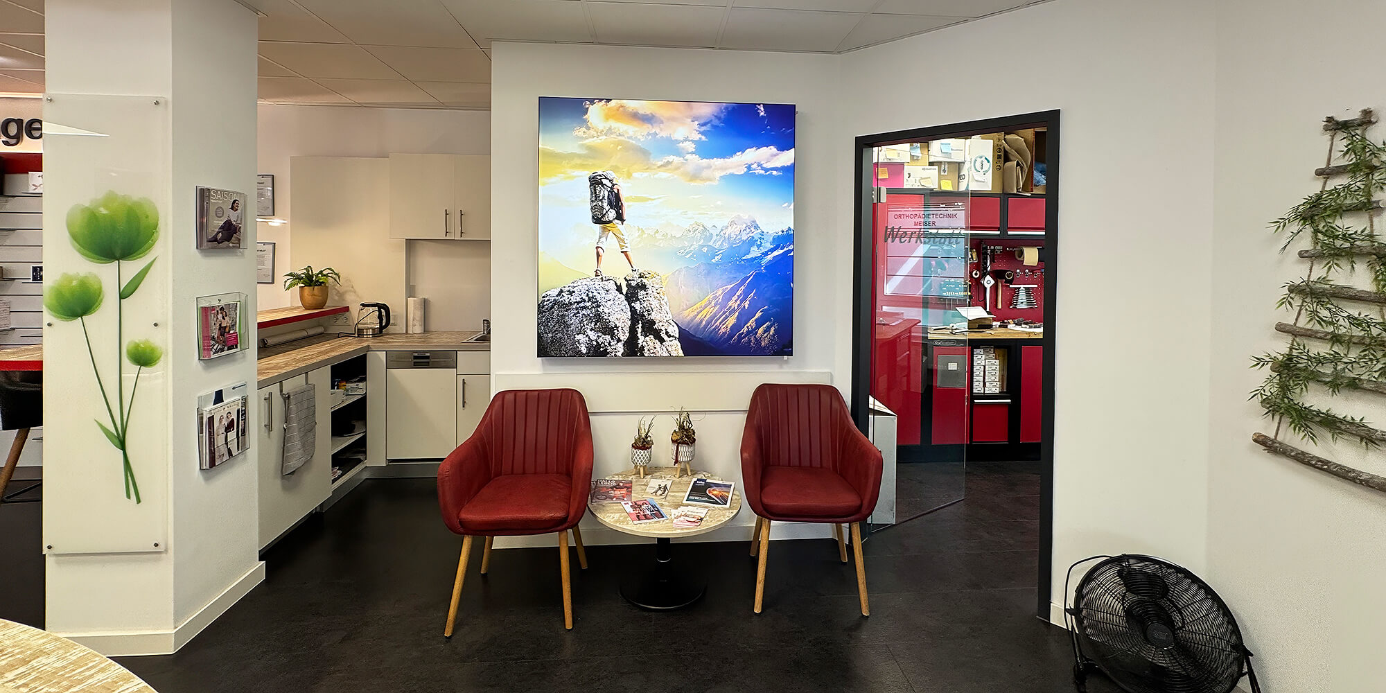 Beratungs- und Aufenthaltsbereich mit Sitzgelegenheiten, Küchenzeile und Wanddekoration